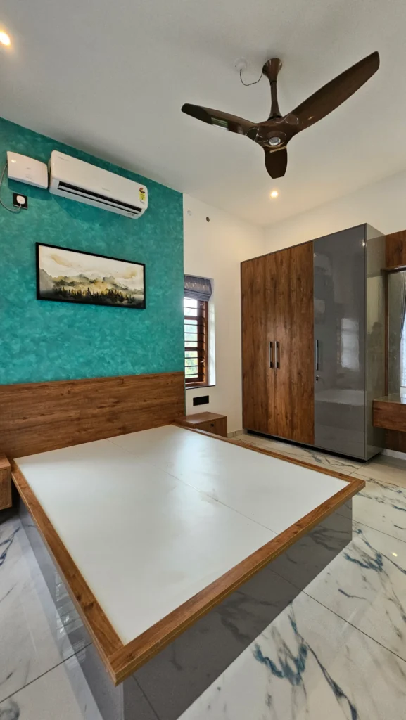 Bedroom with a teal feature wall, timber bed frame and full-height wardrobe