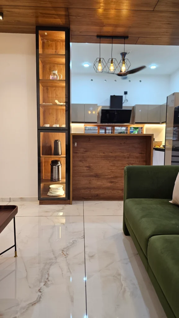 Living area with a green sofa, timber display tower and kitchen counter beyond