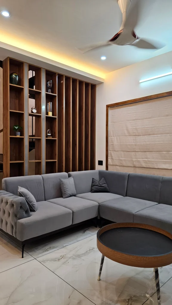 Grey sectional sofa beside timber display shelving with cove lighting