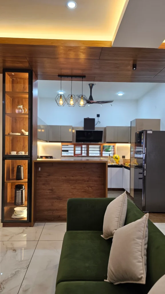Glass-fronted timber display unit and green sofa opening onto the kitchen