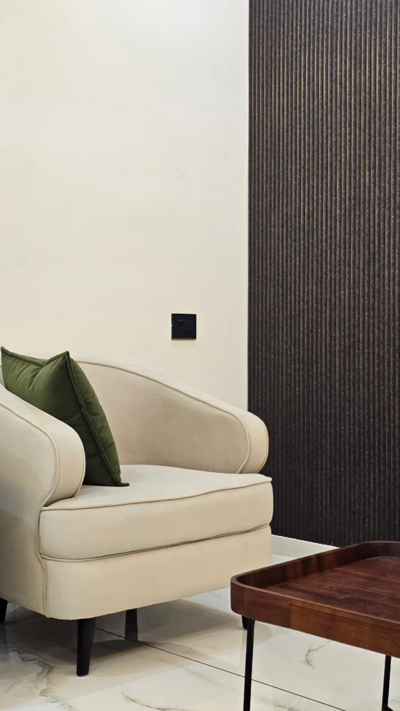 Cream armchair with a green cushion against a fluted dark wall