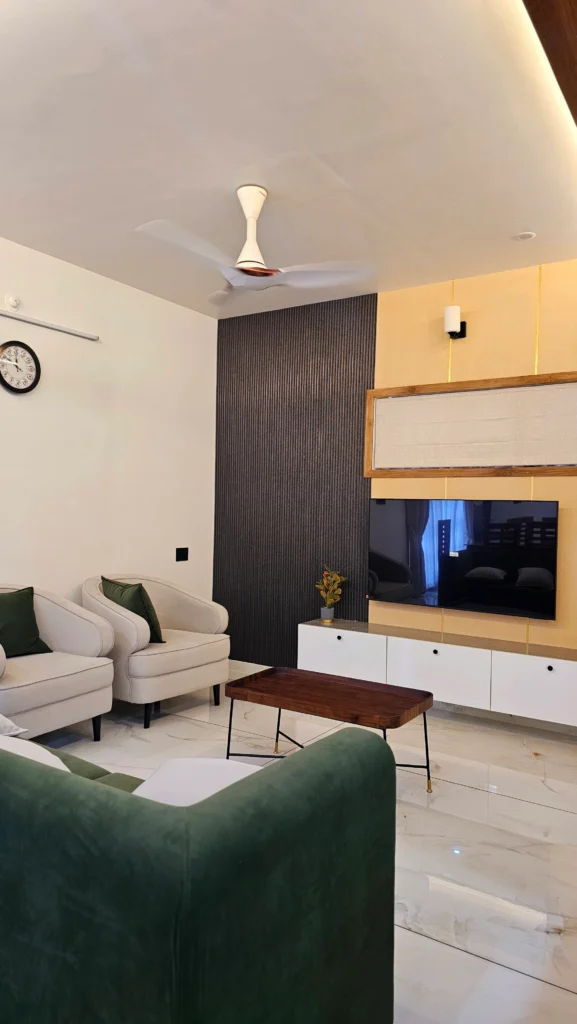 Living room with a fluted dark wall panel, white TV unit and green armchair