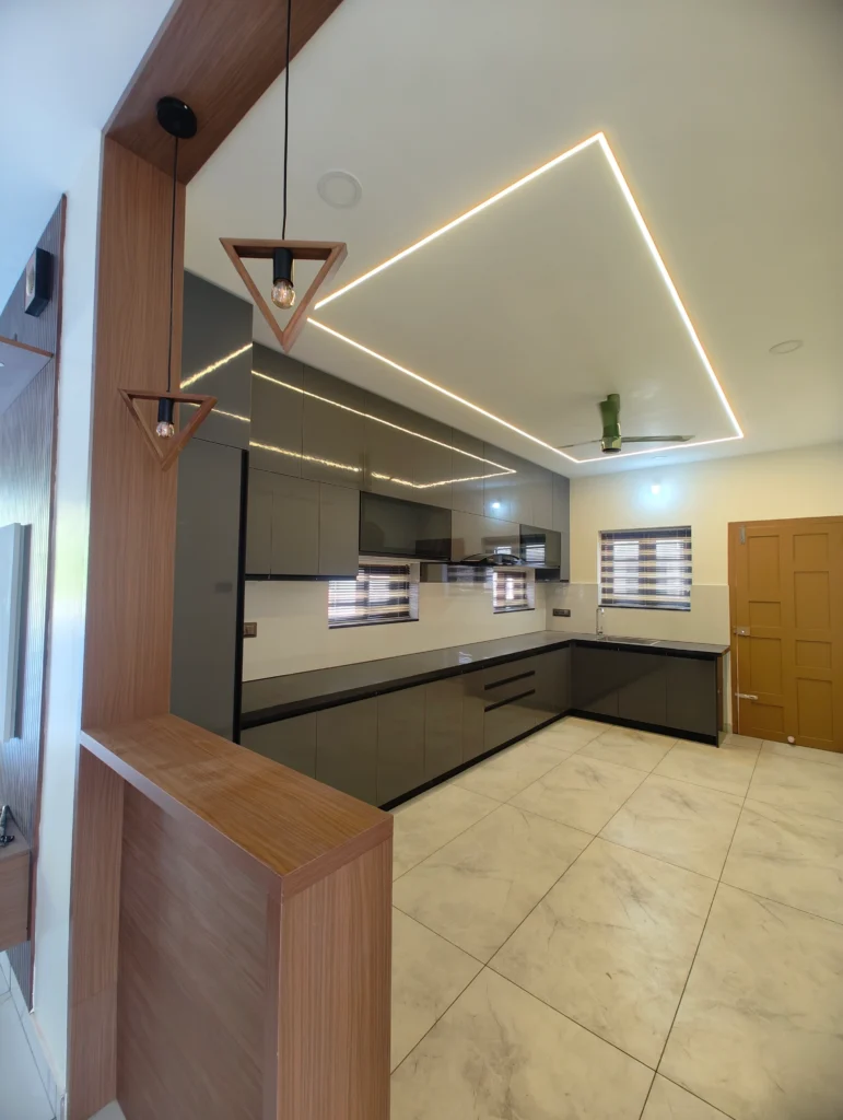 Grey and white L-shaped kitchen beyond a timber partition with linear ceiling lights