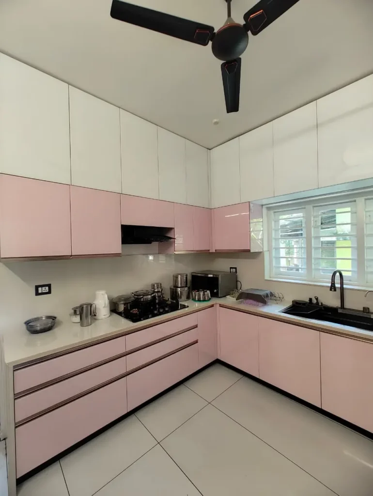 Pink modular kitchen with handle-free drawers and white overhead cabinets, Kollam
