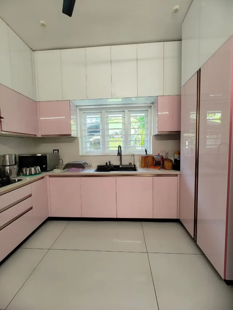 Pink and white kitchen with the sink under the window and tall pink storage