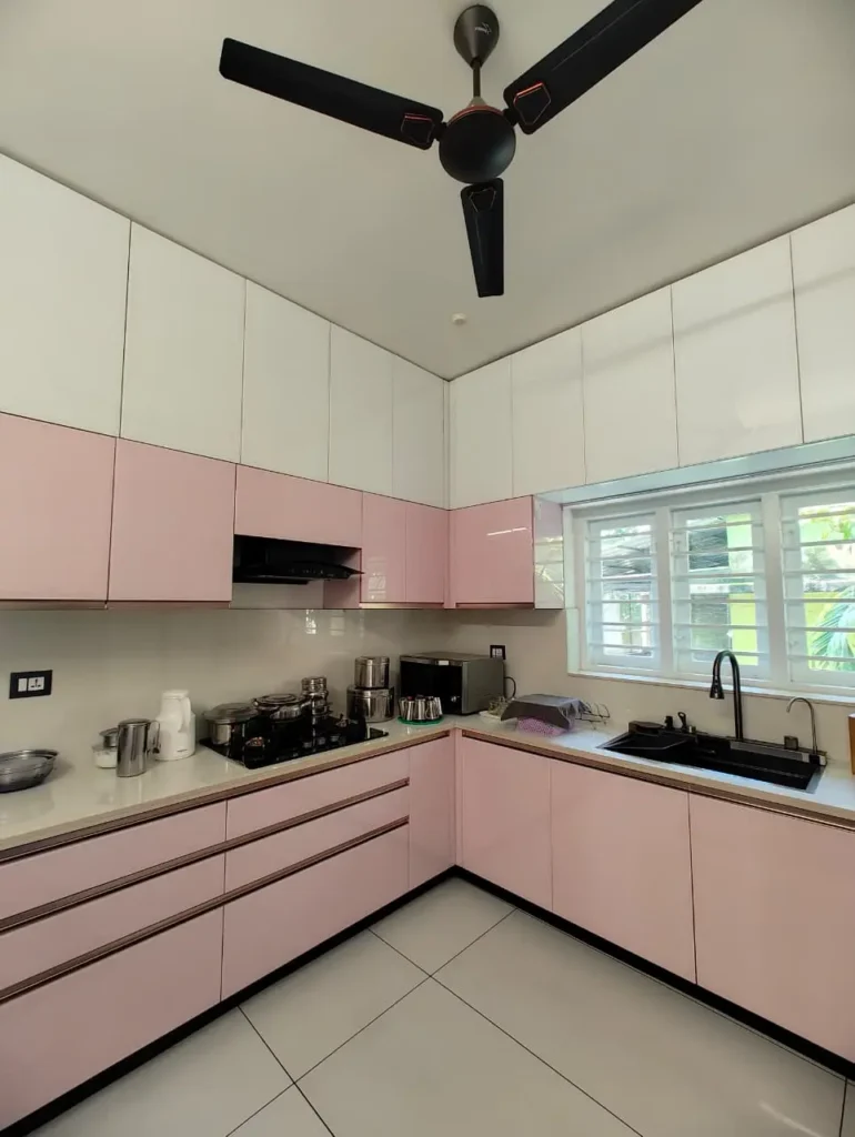 Pink L-shaped kitchen with white high-gloss wall cabinets and drawer stacks