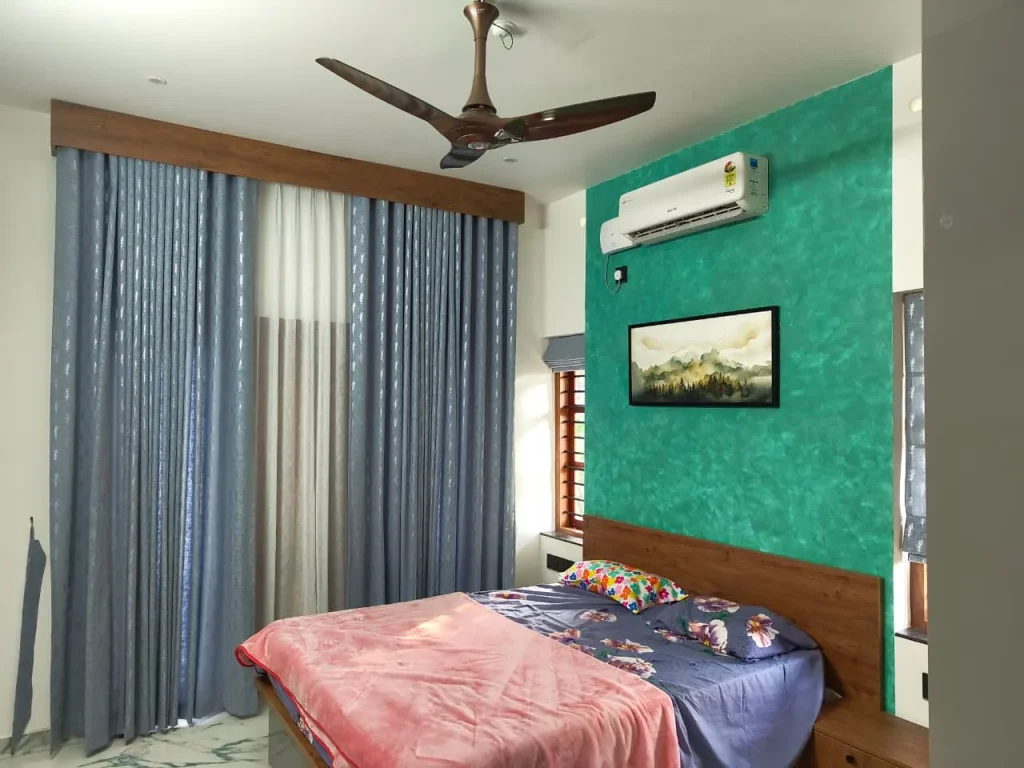 Bedroom with a teal textured wall and blue drapes under a timber pelmet