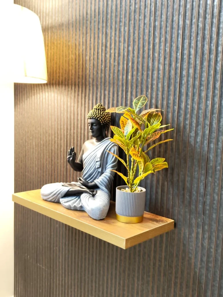 Buddha figure and potted plant on a floating oak shelf against fluted panelling