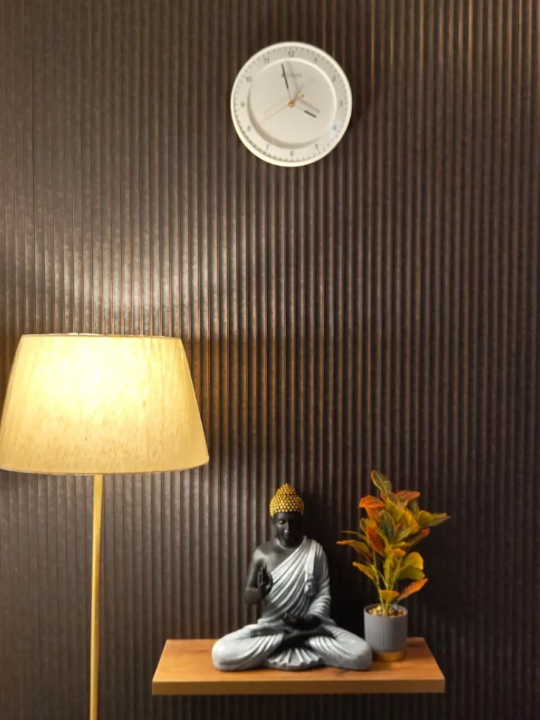 Buddha figure on a floating oak shelf against fluted wall panelling, beside a floor lamp