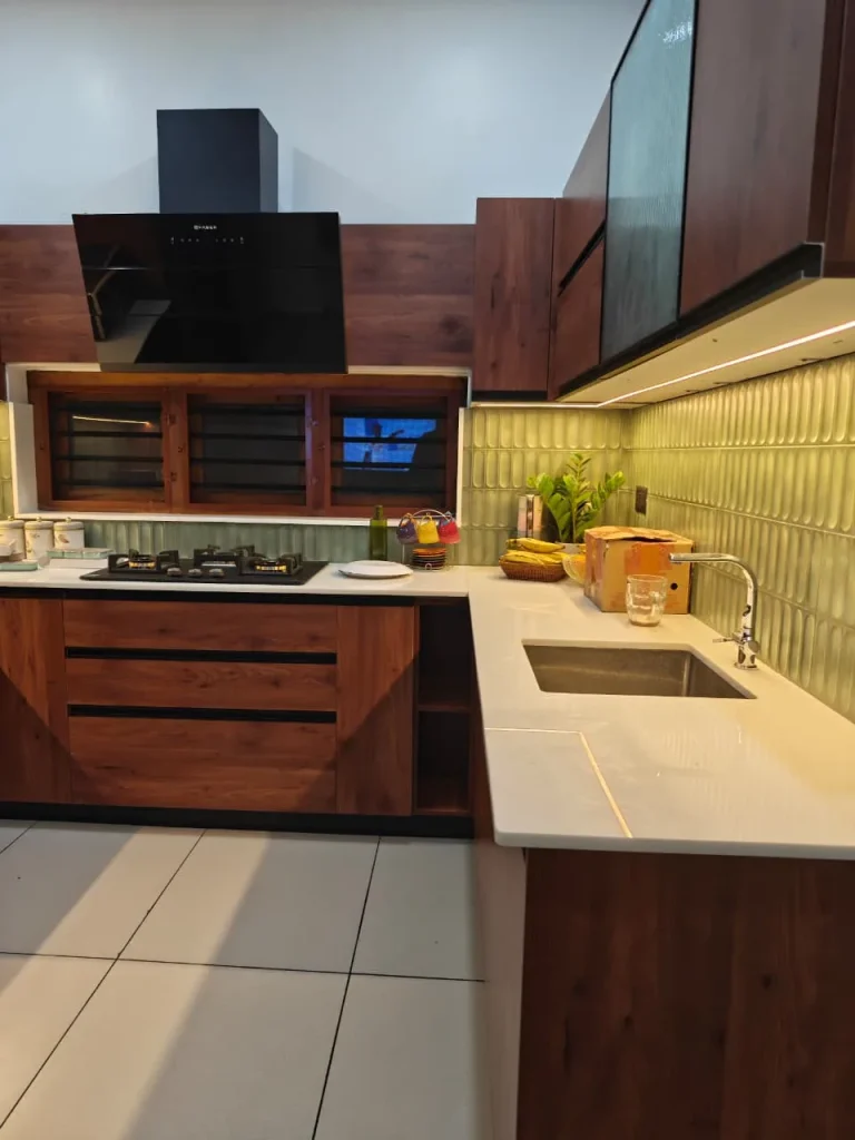 L-shaped walnut kitchen with a white quartz worktop and sage tiled backsplash