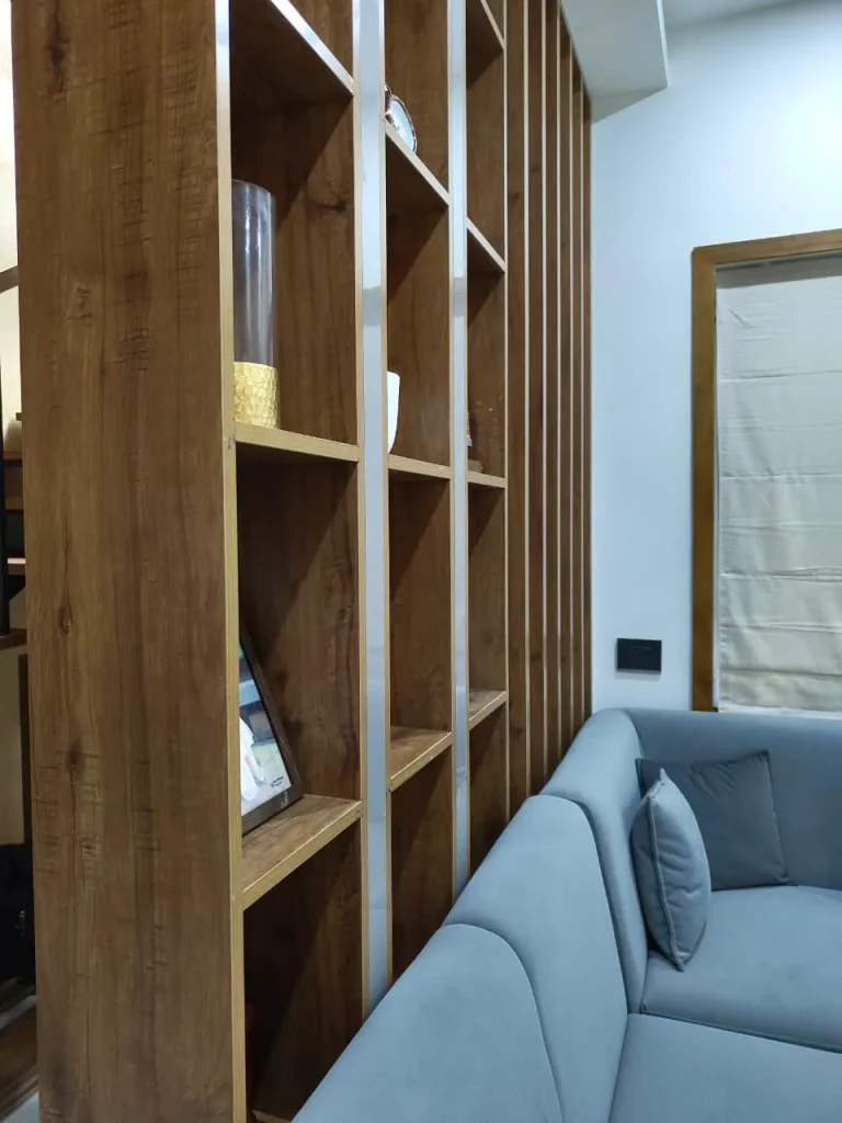 Oak open-shelf partition beside a grey velvet sofa