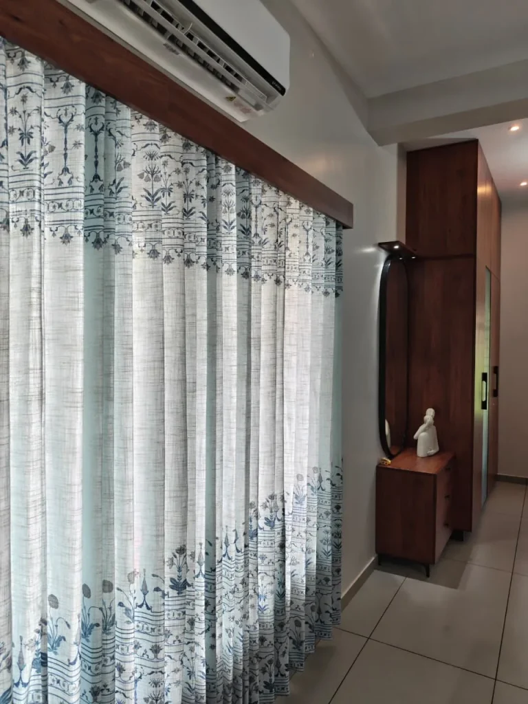 Printed linen curtains under a timber pelmet, with the wardrobe and dresser beyond