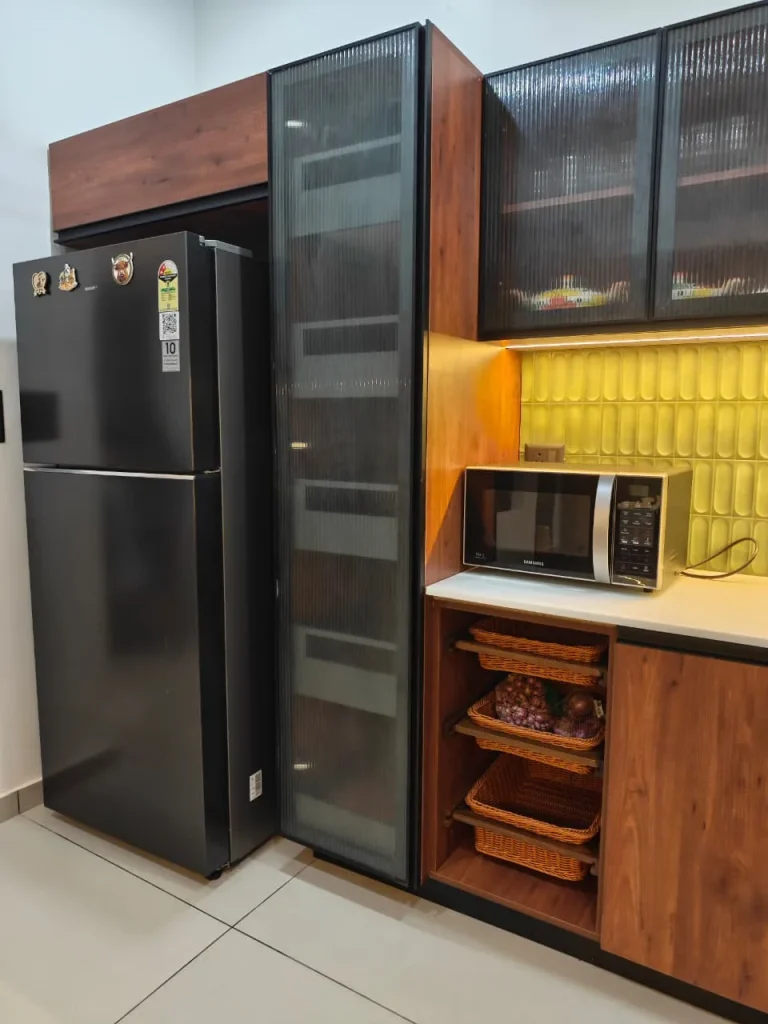 Tall fluted-glass pantry unit beside the fridge, with wicker basket pull-outs