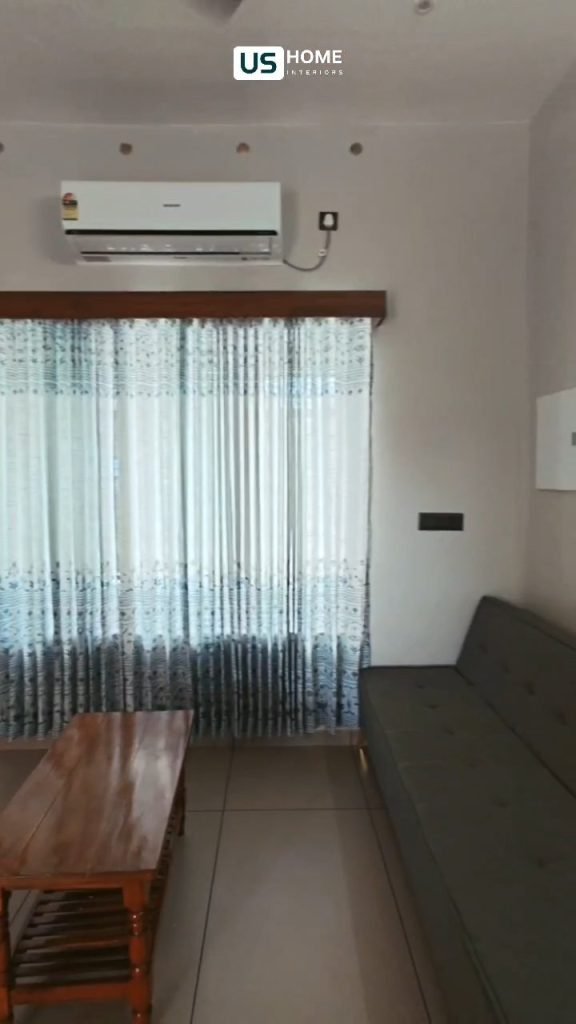 Living area with a dark sofa, timber side table and sheer curtains