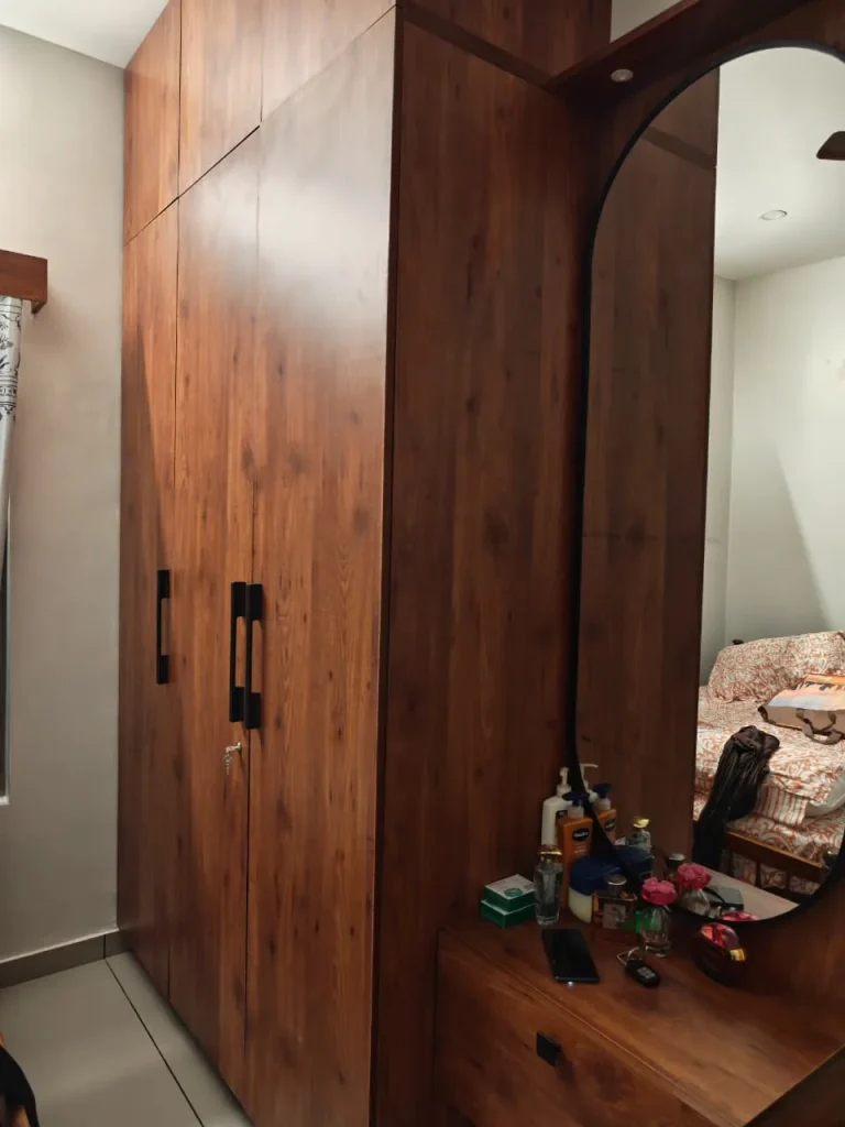 Walnut wardrobe with black handles beside a capsule mirror dresser