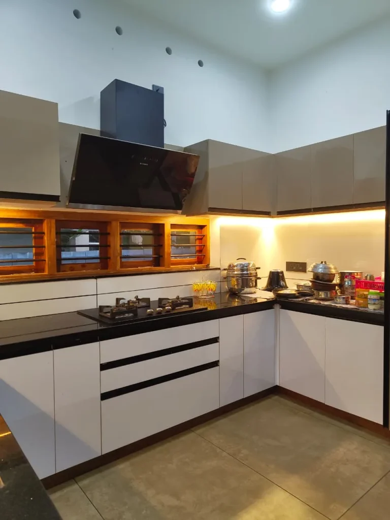 White modular kitchen with drawer stacks, black worktop and angled chimney hood
